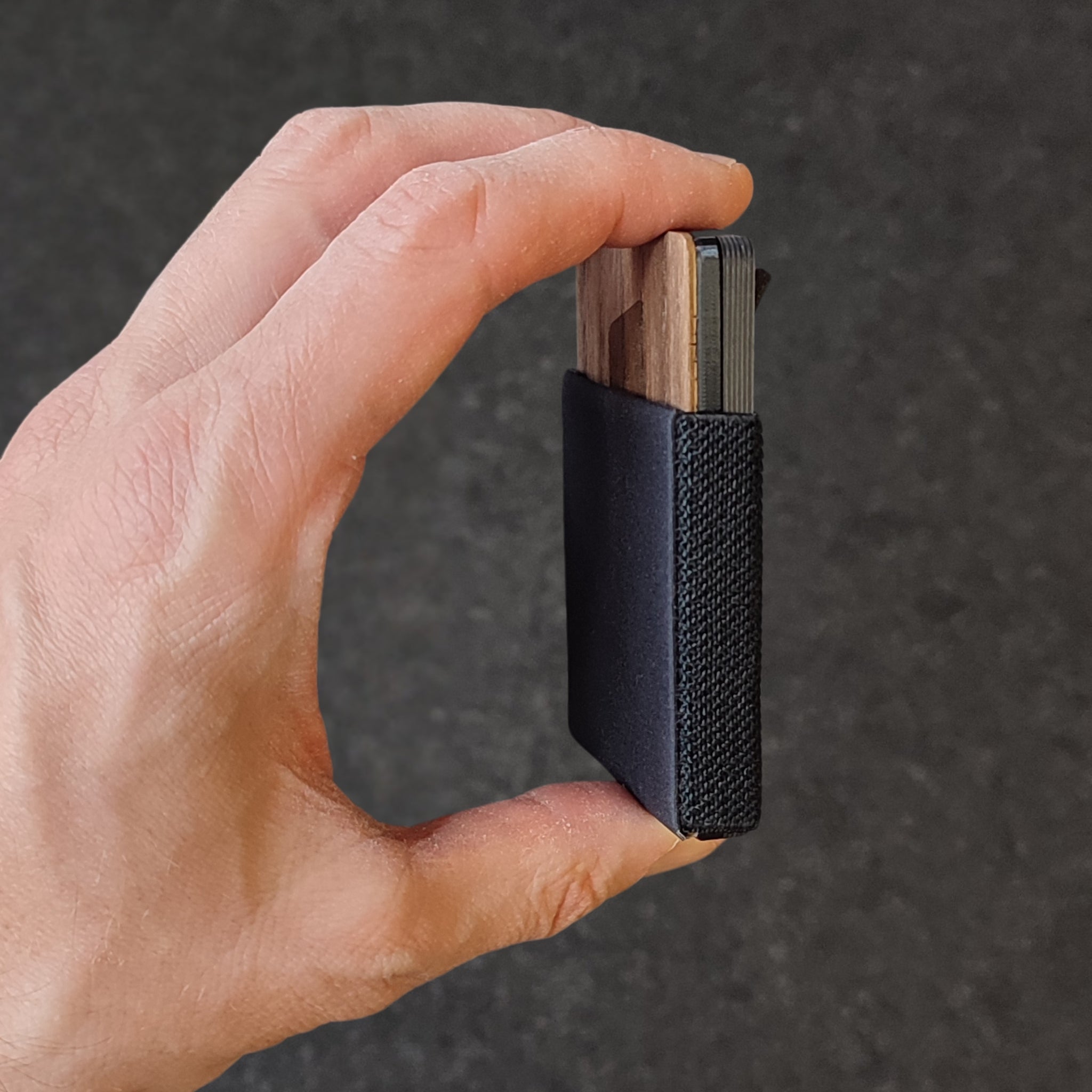 Seitenansicht Canard Essentials Ultralight Explore Slim Wallet zwischen Daumen und Zeigefinger – Echtes Nussbaum Holz