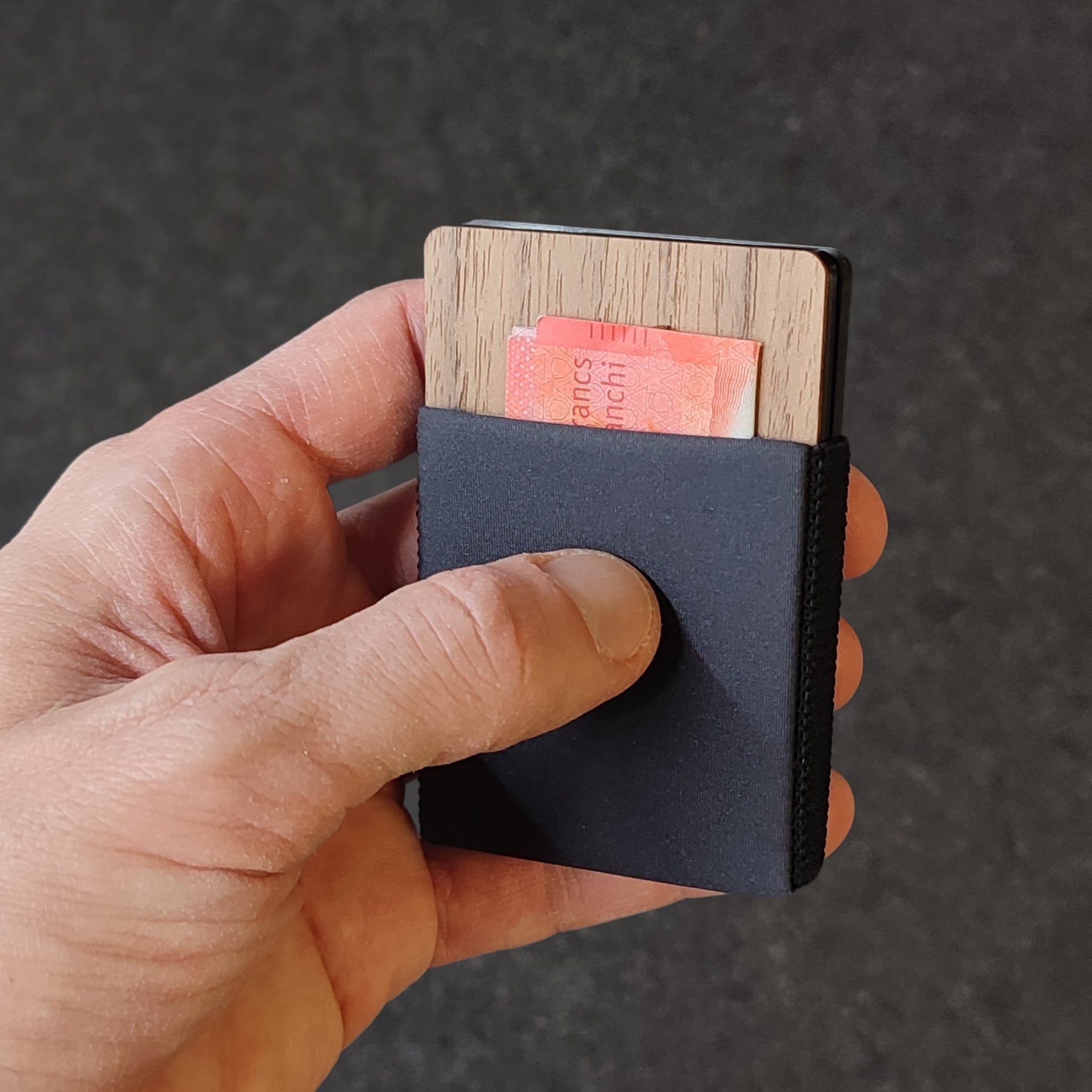 Hand hält Canard Essentials Ultralight Explore Slim Wallet mit Schweizer Geldschein – leichtes minimalistisches Holzkartenetui und Geldscheinfach